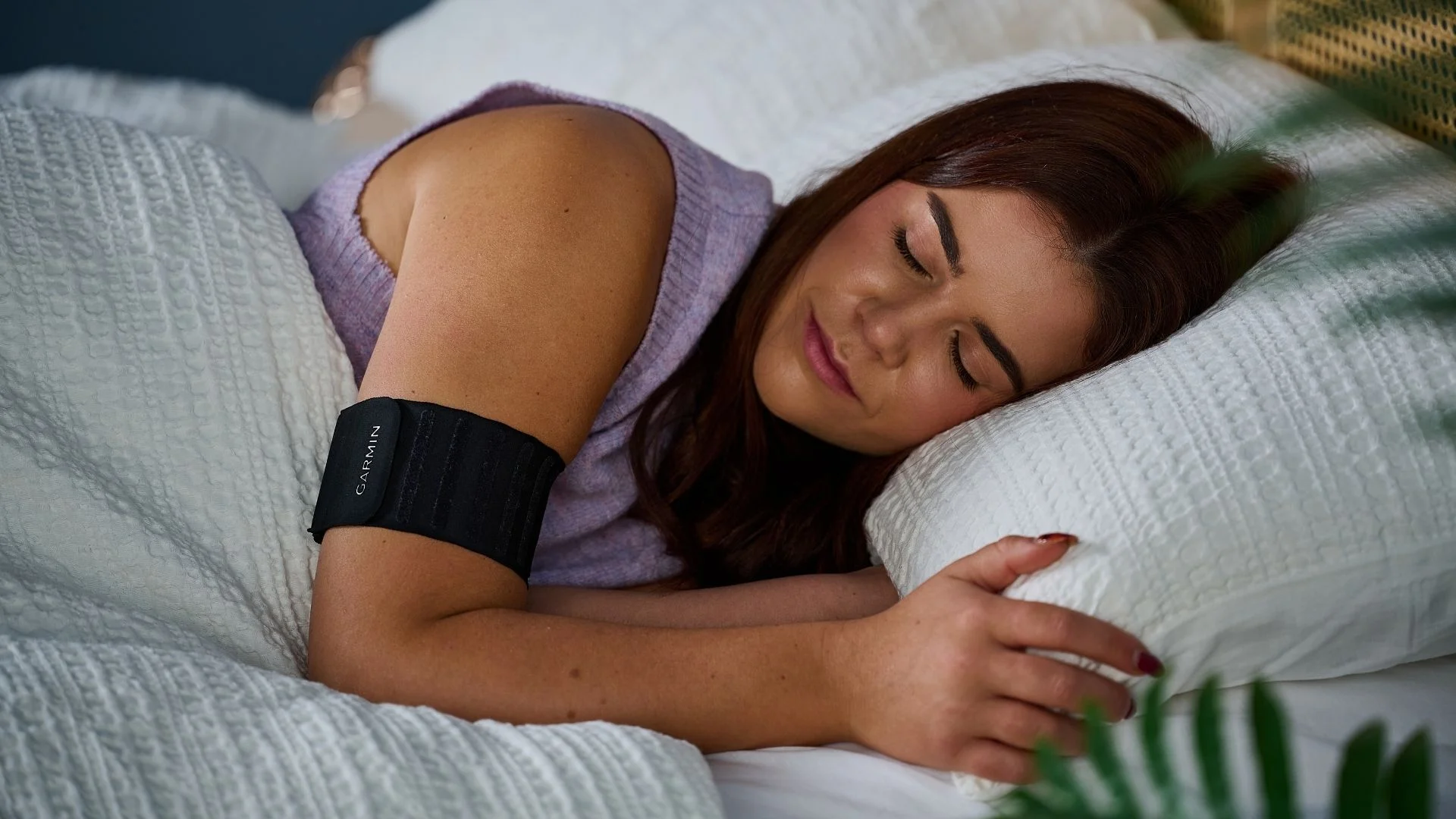 A woman with long brown hair sleeps in a comfortable white bed